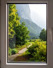 A view from a window looking onto a mountainous landscape with greenery