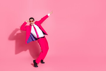Charismatic young man in a vibrant pink suit posing energetically on a pink background reflecting...