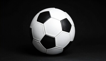 Classic black and white soccer ball with pentagon-hexagon pattern, isolated on solid black background