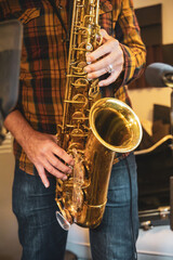 Obraz premium Close-up of hands playing a saxophone in a recording studio environment.