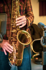 Obraz premium Close-up of hands playing a saxophone in a recording studio environment.