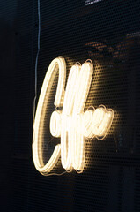 Glowing coffee neon sign on dark perforated wall