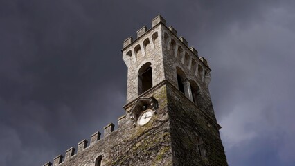 Medieval stone tower clock standing tall against a stormy sky. Action