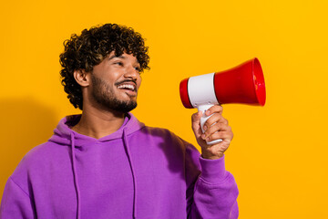 Cheerful man holding a red megaphone against a vibrant yellow background depicting joy and communication in casual attire