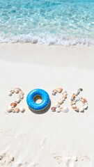 blue inflatable ring rests on sandy beach, adorned with "2026" spelled out in colorful seashells, with ocean and gentle waves in background, evoking relaxed and celebratory atmosphere