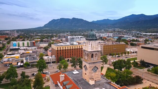 Century old clock tower of the Colorado Springs City Hall. Aerial view on the cityscape surrounded by the mountains.