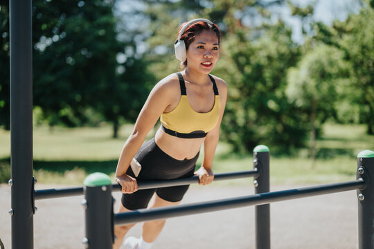 Outdoor fitness with woman using parallel bars for a workout in a sunny park with headphones.