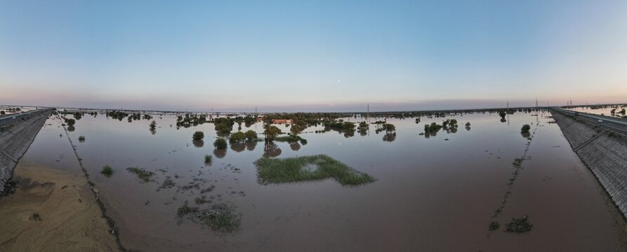 A 180 degrees aerial panorama of a flooded village and its surrounding agricultural land 
