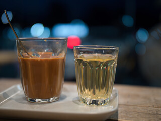 Hot Thai tea and roti drinks at a night shop with lights and bokeh.