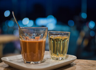 Hot Thai tea and roti drinks at a night shop with lights and bokeh.