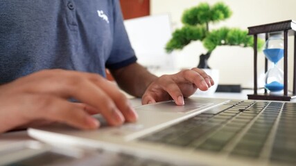 Person typing on a laptop with an hourglass and bonsai tree in the background - Powered by Adobe