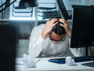 Overwhelmed Asian Businessman Suffering from stress and headache at desk late at night, feeling frustrated with workload and deadline. Asian Male Business manager dealing with business crisis and fail