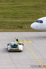 Modern regional jet aircraft towed by ground vehicle on airport taxiway tarmac under sunlight. Engine cockpit clearly visible crew performs technical operations before next scheduled flight airport