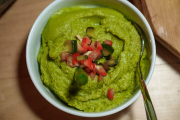 Green sprea of peas, decorated with chopped vegetables such as tomatoes and cucumbers.