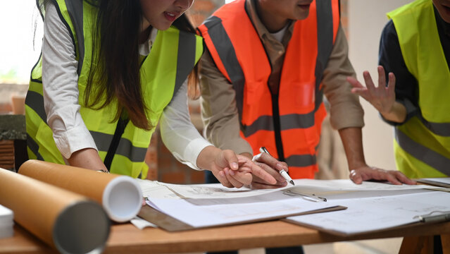 Cropped shot of an engineer, architect and technician analyzing structural design drawings at a construction site meeting