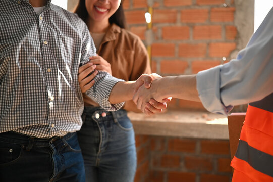 Close-up of homeowners and contractor shaking hands to confirm renovation plans and partnership