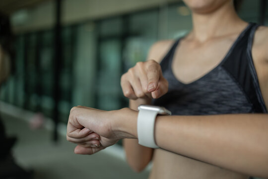 Close up of woman using smart fitness watch before workout at the gym. Concept of modern fitness technology, tracking progress, self monitoring, health awareness and smart active lifestyle.