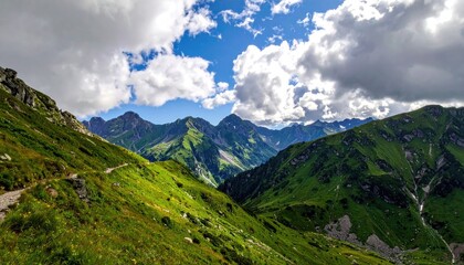 Lush Green Mountain Range With Rocky Peaks Under a Cloudy Blue Sky On a Sunny Day With a Winding Dirt Path in the Foreground