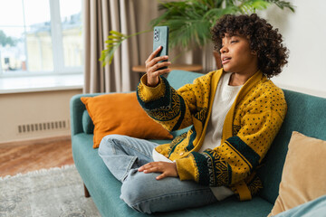 African American girl holding smartphone having video chat. Female blogger chatting with best friends in social network. Young woman having virtual meeting online chat video call at home