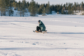 Teenage girl having fun sliding down a snowy hill on a wooden sled in a beautiful winter landscape