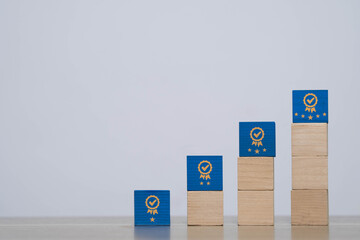 Stacked wooden blocks with award icons and stars representing step-by-step success, growth, improvement, and quality ranking. Perfect for business, education, or career progress themes.