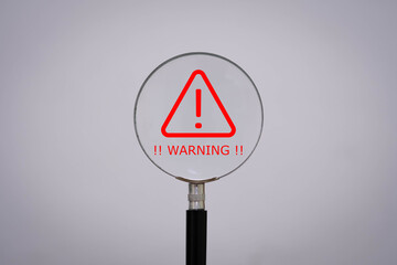 Magnifying glass highlighting a red warning symbol with exclamation mark, representing alert, caution, or risk. Ideal for cybersecurity, safety, and critical messages.
