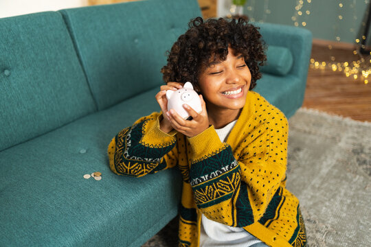 Saving money investment for future. African American girl holding pink piggy bank and putting money coin. Saving investment budget business wealth retirement financial money banking concept