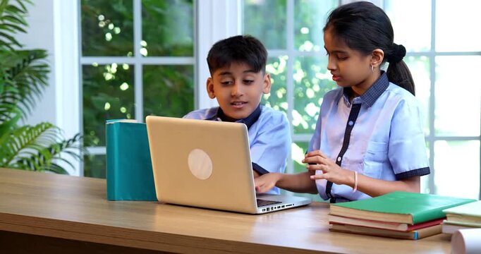 Indian School Kids Studying Together on Laptop in Classroom While Wearing School Uniforms, Group Learning, Sharing Knowledge, Collaborating on Academic Tasks Using Technology During Education Session