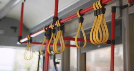 Close up of yellow hand grips on red poles inside a public bus, showcasing public transport interior design.