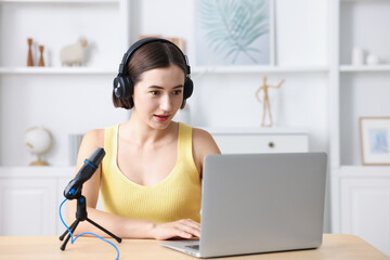 Podcast host recording episode with microphone and laptop indoors