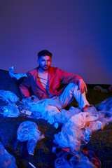 Fototapeta premium Young man surrounded by plastic waste highlights urgent environmental issues