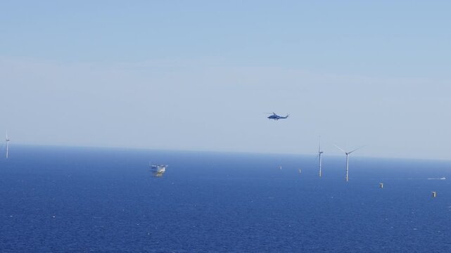 Video footage of a helicopter flying into an offshore wind farm in the Baltic Sea taken from a helicopter.