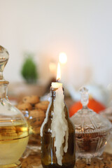 Lit candles, cookies, chocolate, nuts, tea, wine, pumpkins, books, reading glasses and autumn leaves on the table. Autumnal hygge at home. Selective focus.
