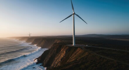 Coastal wind turbines at sunset.  Ocean waves crash on a cliffside.  Vast landscape stretches to a hazy horizon