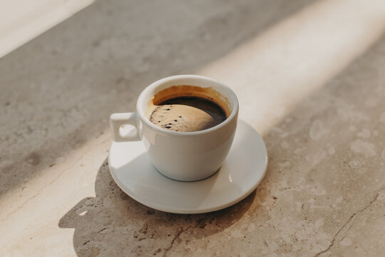 Cup of black coffee on a marble table in a cafe in a sunlight. Natural warm colors.