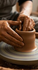 Hands shaping wet clay on a spinning pottery wheel.