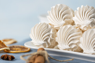Whipped meringue cookies arranged on a white plate, accompanied by a cup of dark coffee, cinnamon...