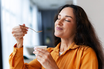 Woman enjoying healthy yogurt snack with closed eyes