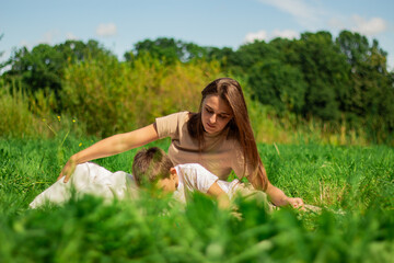 Mother with kid having fun in public green park. Happy mom laughing together with son. Quality...
