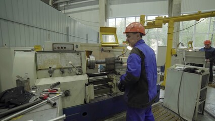 Factory worker operating lathe machine manufacturing metal part. Stock clip