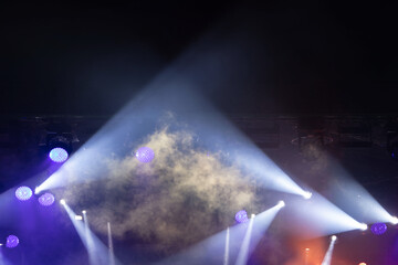 Colorful stage lights illuminate the atmosphere during a live concert event at night in an urban setting