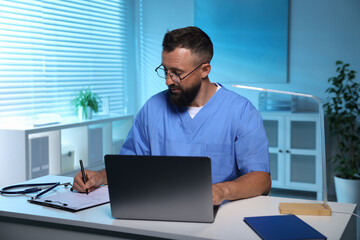 Fototapeta premium Doctor working at table in clinic during night shift