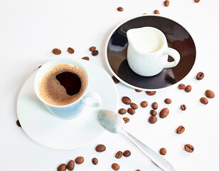 Coffee in a blue cup sits on a white table with coffee beans scattered nearby.