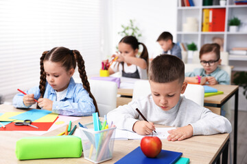 Children drawing at wooden desk during art lesson in elementary school