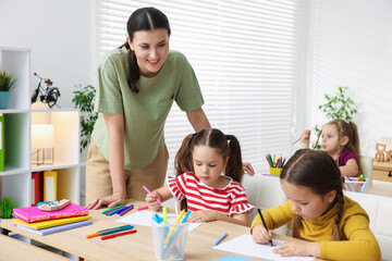Obraz premium Children having lesson with teacher at wooden desks in elementary school