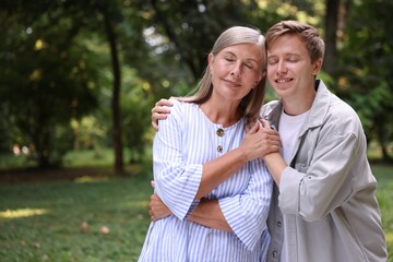 Obraz premium Mother and her happy son outdoors, space for text. Family bonding