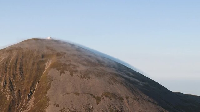 Amazing 4K aerial video of flying above and around Most Famous mountain in Ireland - Croagh Patrick in windy weather, with moving fog and clouds with breathtaking views around, Westport, Ireland