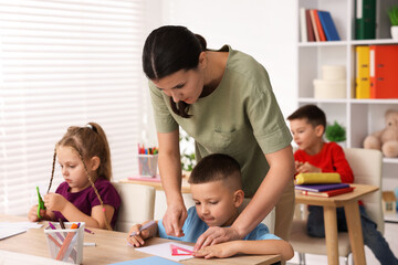 Fototapeta premium Children having lesson with teacher at wooden desk in elementary school