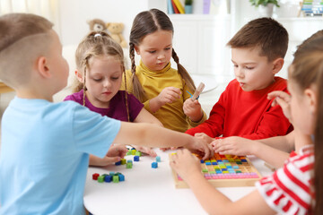 Fototapeta premium Cute children at white table during lesson in elementary school
