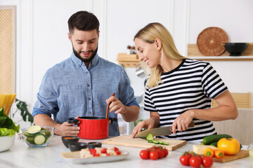 Happy couple cooking together at table in kitchen